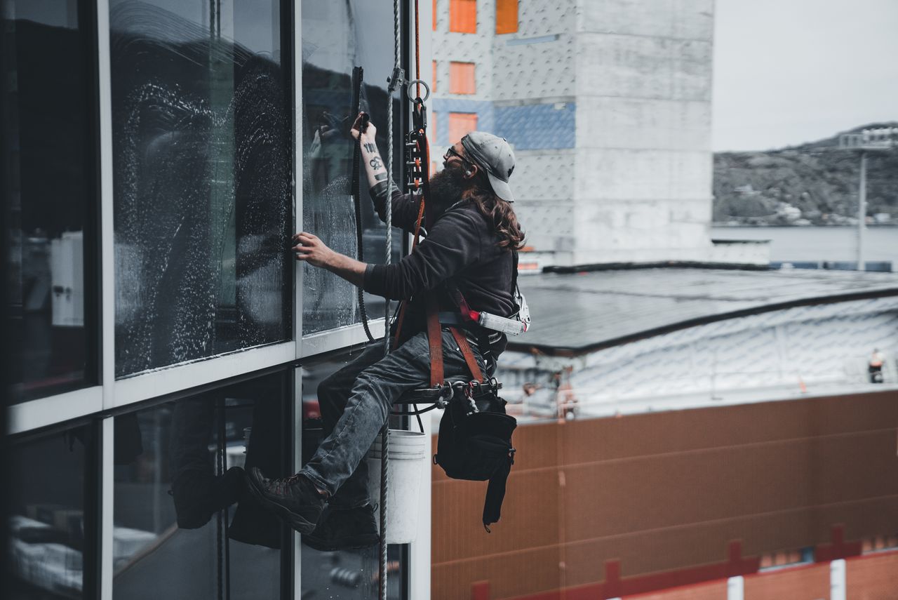 project-02-b A man cleaning skyscraper windows with a harness, showcasing urban high-rise work.