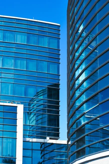 Two workers cleaning windows on a glass building facade using a lift platform, enhancing building aesthetics.